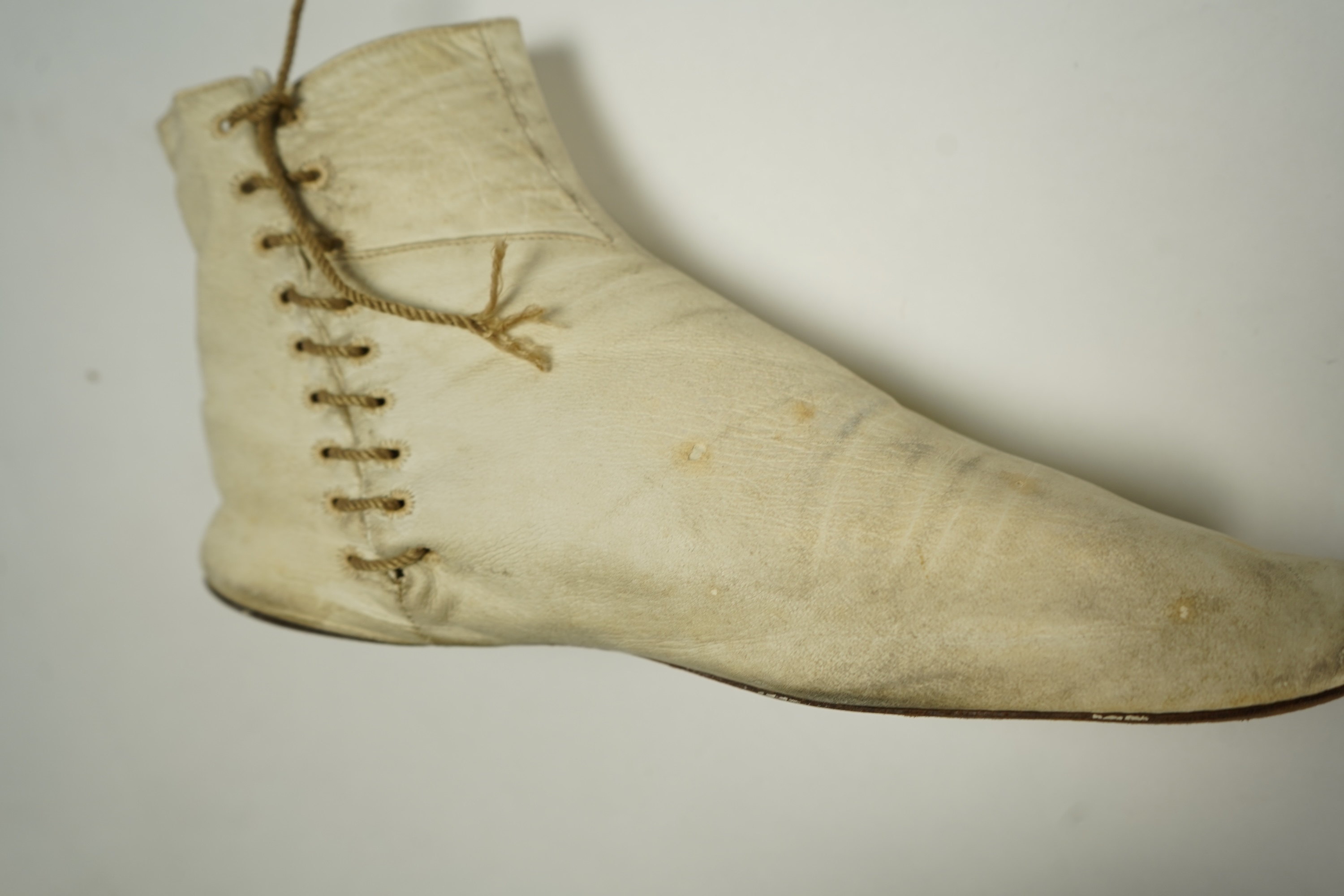 A 19th century hand made cream kid leather ladies ankle boot and four differing cream silk and satin single wedding shoes. All with leather soles. Possibly a traveller's sample range. Boots 24.5cm long (heel to toe). Con